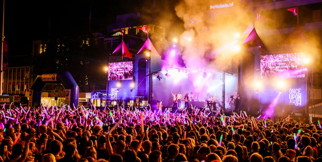 A crowd with glow sticks at an open-air festival stage in Groningen at night